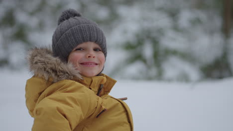 Porträt-Eines-Lächelnden-Süßen-Jungen-Im-Alter-Von-3-4-Jahren,-Der-Mit-Einem-Glücklichen-Lächeln-Auf-Der-Straße-Im-Winter-Im-Wald-In-Zeitlupe-In-Die-Kamera-Blickt